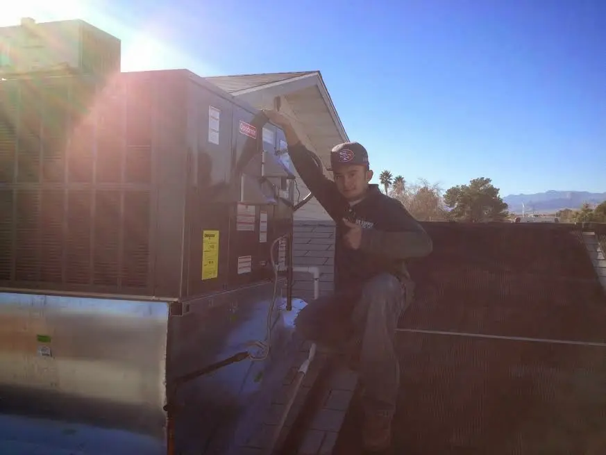 HVAC technician performing AC Tune-Up on a rooftop unit in Ambridge